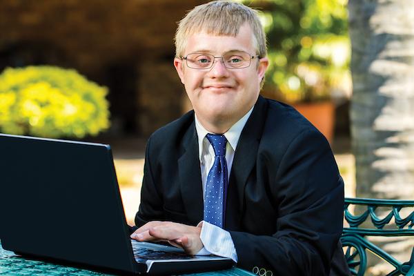 Student working on laptop outside on campus.